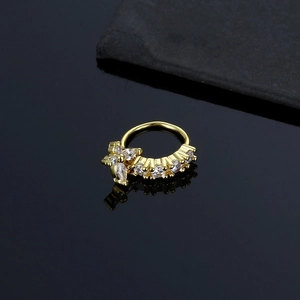 Golden nose ring with crystal clusters and butterfly pendant on reflective black surface
