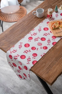 Close-up of Christmas table runner with red candy patterns on dark wood tabletop