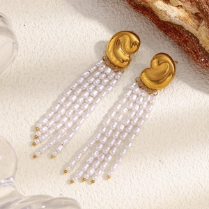 Détail macro de boucles d'oreilles pampilles dorées 18K avec perles blanches nacrées