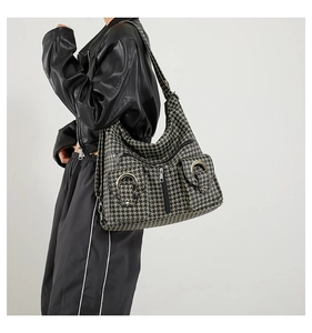 Detail of crossbody bag with houndstooth pattern and metallic ring on model in leather jacket
