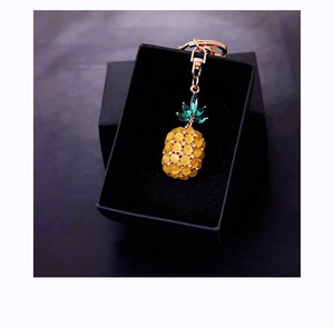 Detail of opal pineapple keychain with gold metal clasp on a black gift box
