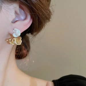 Close-up of model wearing retro irregular pleated gold and white petal earrings