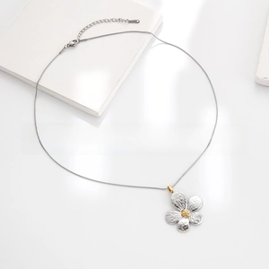 Detailed macro of silver flower pendant with gold center and hammered metal texture