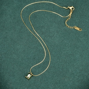 Detail of gold titanium steel necklace with emerald green zircon and K18 hallmark stamp
