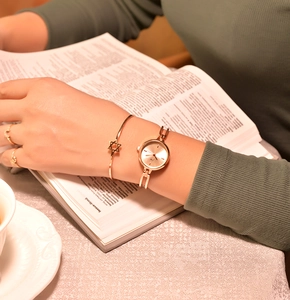 Detail of a minimalist gold watch and star bracelet on a wrist during reading
