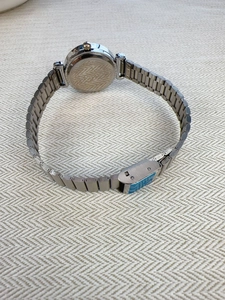 Detail of silver quartz watch featuring metal link strap and secure case back on fabric