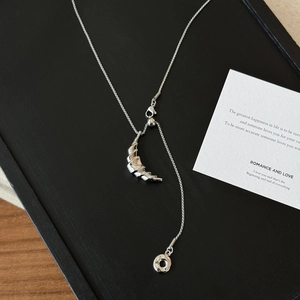 Silver croissant pendant necklace with minimalist texture on a dark textured display