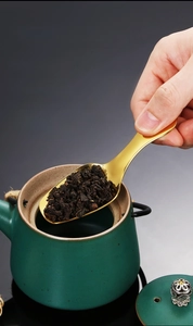 Close-up of a deep golden stainless steel tea scoop for precise loose leaf measuring