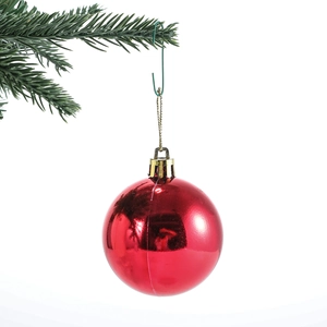 Red Christmas tree ornament ball hanging on a pine branch with a sturdy metal S-hook