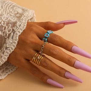 Close-up of elegant gold ring set with blue floral beads and colorful crystals