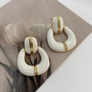 Detailed close-up of French vintage U-shaped earrings in white enamel and gold plating