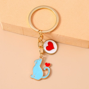 Close-up of blue cat and red heart pendants on a gold keychain with wooden background
