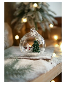 Detail of Christmas glass ornament featuring miniature snowman and tree in snowy scene