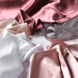 Detailed view of folded satin silk scarves showing glossy texture and various colors