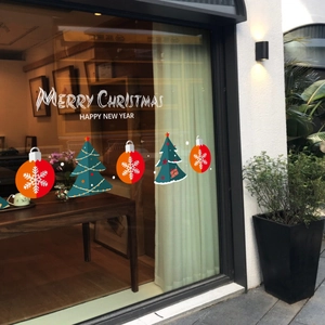 Weihnachtsaufkleber mit Tannen und Flocken auf einer Glastür in einer warmen Ladenumgebung