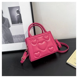 Détail du sac bandoulière rose fuchsia avec motifs de cœurs en relief et texture cuir PU