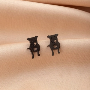 Detailed close-up of cute black pug puppy stud earrings on pink satin fabric background