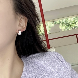 Minimalist silver geometric polygon earrings worn by model in natural outdoor setting