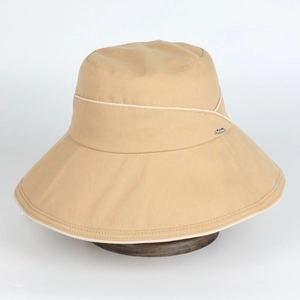 Détail d'un chapeau de soleil beige à large bord en sergé de coton avec logo en métal