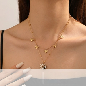 Dettaglio della collana dorata a due strati con ciondoli a margherita e ape