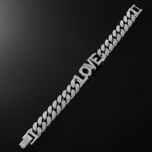 Macro shot of silver Cuban link bracelet with rhinestone-encrusted LOVE letter pendant