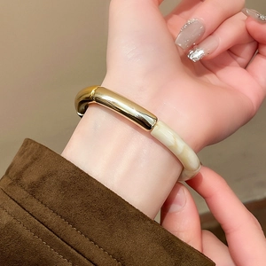 Detail of a wide irregular bangle featuring polished gold metal and marble texture resin