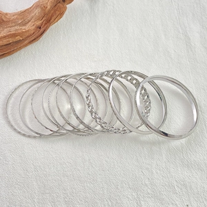 Detailed view of 10-piece silver alloy bangles featuring smooth, twisted, and textured designs