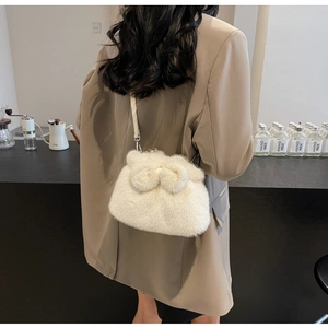 White faux fur handbag with bow detail and silver hardware shown on a model