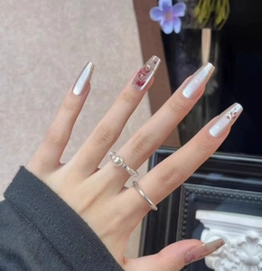 Makroansicht langer Ballerina-Klebenägel mit silbernem Katzenauge und rotem Blumendesign