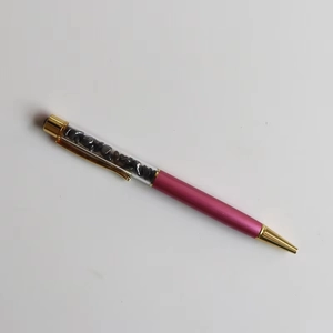 Macro detail of luxury ballpoint pen with black crystal stones and rose red metal barrel