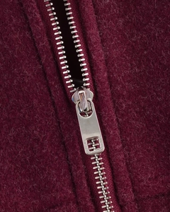Détail macro du tissu en laine bordeaux avec une fermeture éclair en métal argenté de qualité