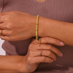 Detail of light green natural stone beaded bracelet with gold accents on model wrist