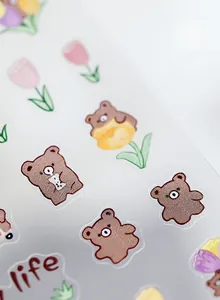 Macro shot of thin nail art stickers featuring cute brown bears and pink tulips designs