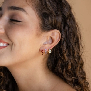 Tre orecchini a lobo con pietre natali placcati oro 18k mostrati su una modella