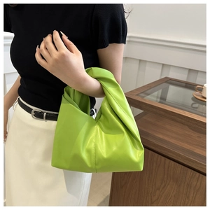 Detailed view of neon green pleated bucket bag with a unique knot handle design