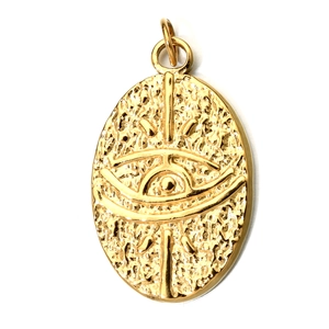 Macro view of golden oval pendant with detailed eye motif relief and textured metal finish