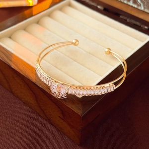 Macro detail of gold double-layer rose bracelet featuring cubic zirconia flower inlay