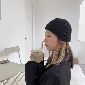 Close-up of a black ribbed knit beanie paired with a minimalist black blazer