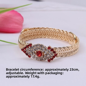 Detail of stretchable gold woven bracelet with red and white rhinestone flower charm