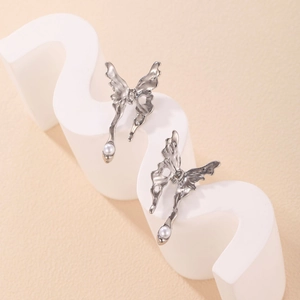 Detail of silver fluid butterfly earrings with white pearl accents on modern display