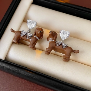 Detail of brown dachshund earrings featuring silver bows and clear heart cubic zirconia