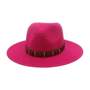 Détail d'un chapeau fedora en paille fuchsia avec bande en cuir et rivets décoratifs