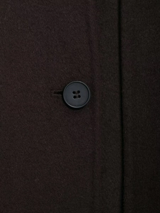 Macro detail of high-quality wool blend fabric and a black round button on a winter coat