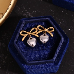 Détail des boucles d'oreilles nœud et cœur dans un écrin en velours au fini brillant