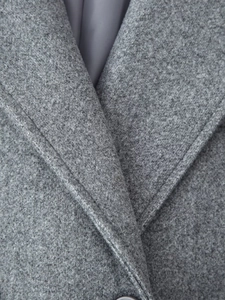 Primo piano del bavero e delle cuciture di questo cappotto in lana grigia