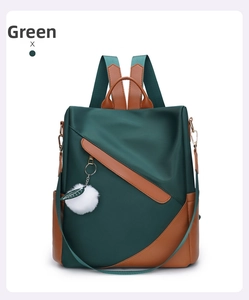 Detail of green waterproof nylon backpack with brown leather trim and plush ball charm