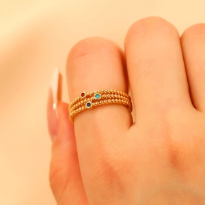 Detailed macro view of gold-plated triple-layered beaded ring with colorful gemstones