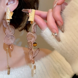 Macro shot of long tassel earrings with silk petals and amber beads on a female model