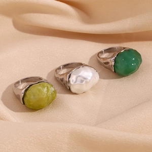 Detailed view of three rings with colorful irregular resin stones on soft beige fabric
