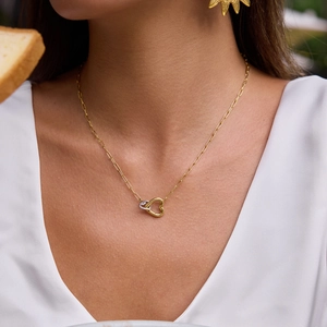 Close-up of a gold necklace featuring interlocking gold and silver heart-shaped pendants